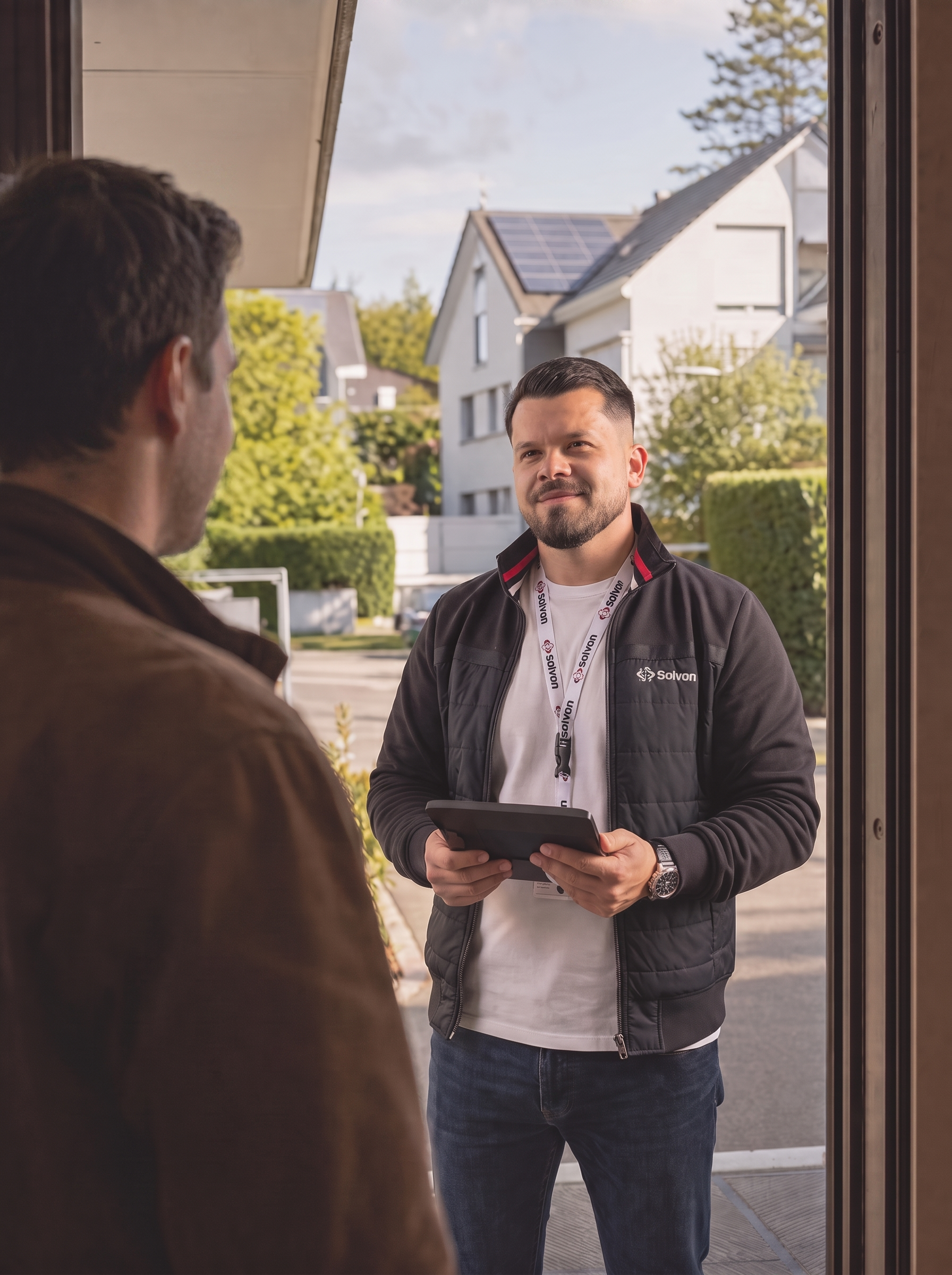 Solvon-Chef mit Tablet im Gespräch mit einem Hauseigentümer an dessen Haustür