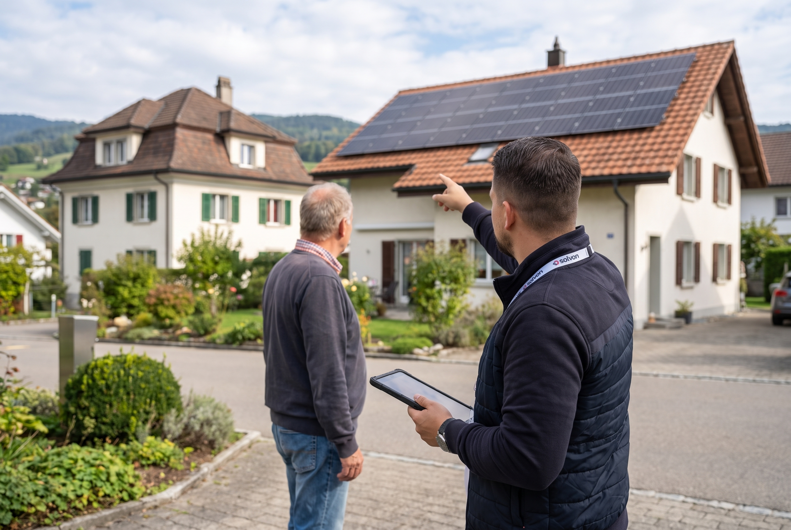 Solvon-Mitarbeiter zeigt einem Hauseigentümer eine Photovoltaikanlage auf einem Nachbardach